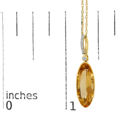 Close-up image of a yellow necklace pendant featuring an elongated oval yellow gemstone in a prong setting, accented by white round gemstones in a micro-pave setting above it, shown hanging on a chain against a background with measurement markings.
