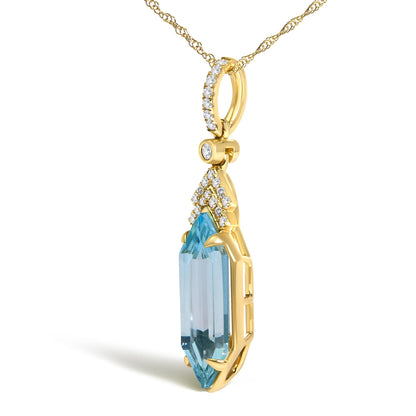 Close-up front angle of a yellow necklace pendant with a large blue gemstone in a prong setting, surrounded by small white gemstones in a micro-pave setting, also featuring a circular element with additional white gemstones, shown on a white background.