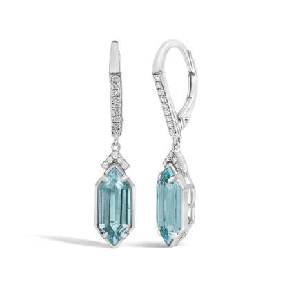 Close-up front angle of yellow metal drop earrings featuring round white gemstones in micro-pave setting along the top and a large vertical blue gemstone in prong setting at the bottom.