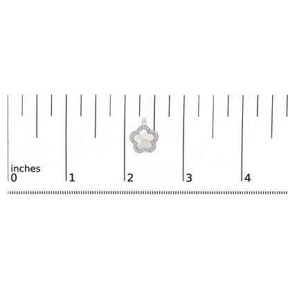 White metal flower-shaped earring with white mother of pearl center and micro-pave white gemstones around the edge, shown on a scale.