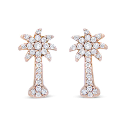 Front view of rose metal earrings shaped like stylized palm trees, adorned with round white gemstones in prong settings.