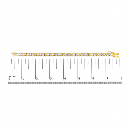 Yellow bracelet with round white gemstones in 4-prong settings shown on a flat surface next to a measurement scale, image taken from above.