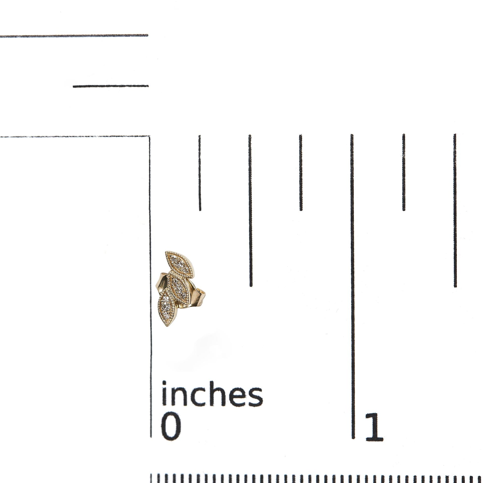 Close-up front view of a yellow metal earring with a cluster of marquise shapes, each set with small white gemstones, placed on a ruler for size reference.