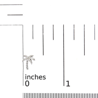 Close-up front view of a white metal palm tree-shaped earring with round white pave-set gemstones, placed on a ruler for size reference.