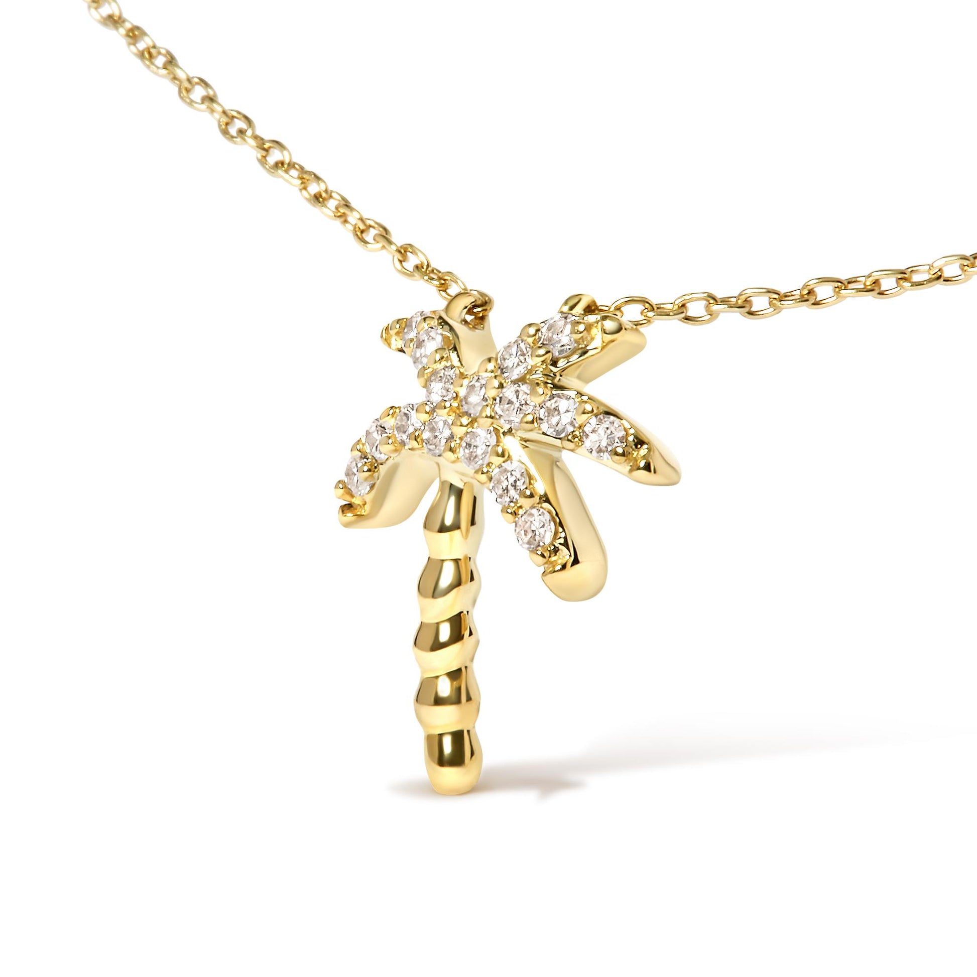 Close-up front angle of a yellow metal necklace with a palm tree pendant decorated with white round pave set gemstones.