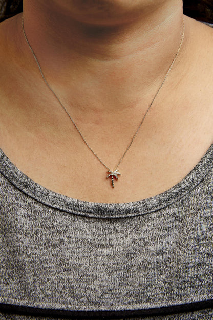 Yellow metal necklace with a palm tree pendant featuring white round pave-set gemstones, worn on a model, front view.