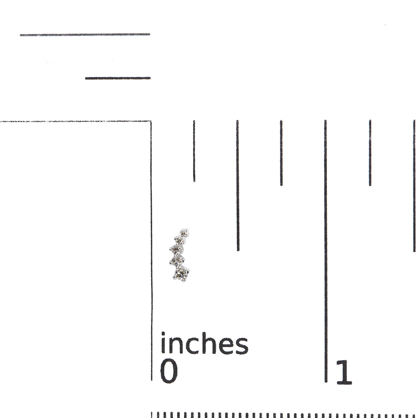 Close-up image of a white metal earring with multiple small round white gemstones in prong settings, shown on a ruler for size reference.