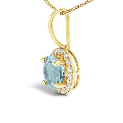 Close-up angled view of a yellow metal necklace pendant featuring a round blue gemstone in a four-prong setting, surrounded by small white round gemstones in a shared prong setting.