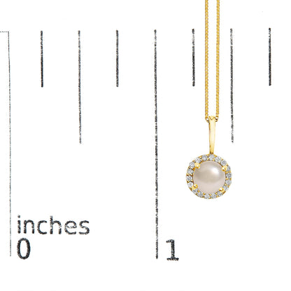 Yellow metal necklace with a round pendant featuring a central smooth white gemstone surrounded by a halo of small round white gemstones in a shared prong setting, shown on a scale from a front angle.