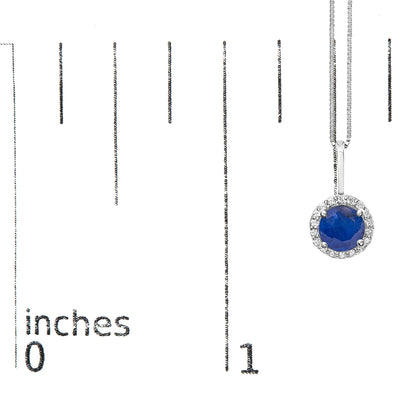 White metal necklace with a round blue gemstone pendant surrounded by small round white gemstones, shown on a scale from 0 to 1 inch, front view.