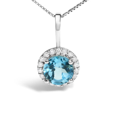 Close-up front view of a white metal necklace featuring a round blue gemstone in a four-prong setting surrounded by a circle of small round white gemstones in a shared prong setting.