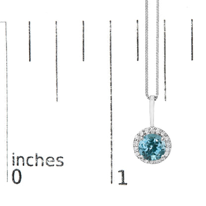Close-up front angle of a white necklace pendant shown on a scale, featuring a round blue gemstone in a four-prong setting surrounded by a halo of round white gemstones in a shared prong setting.