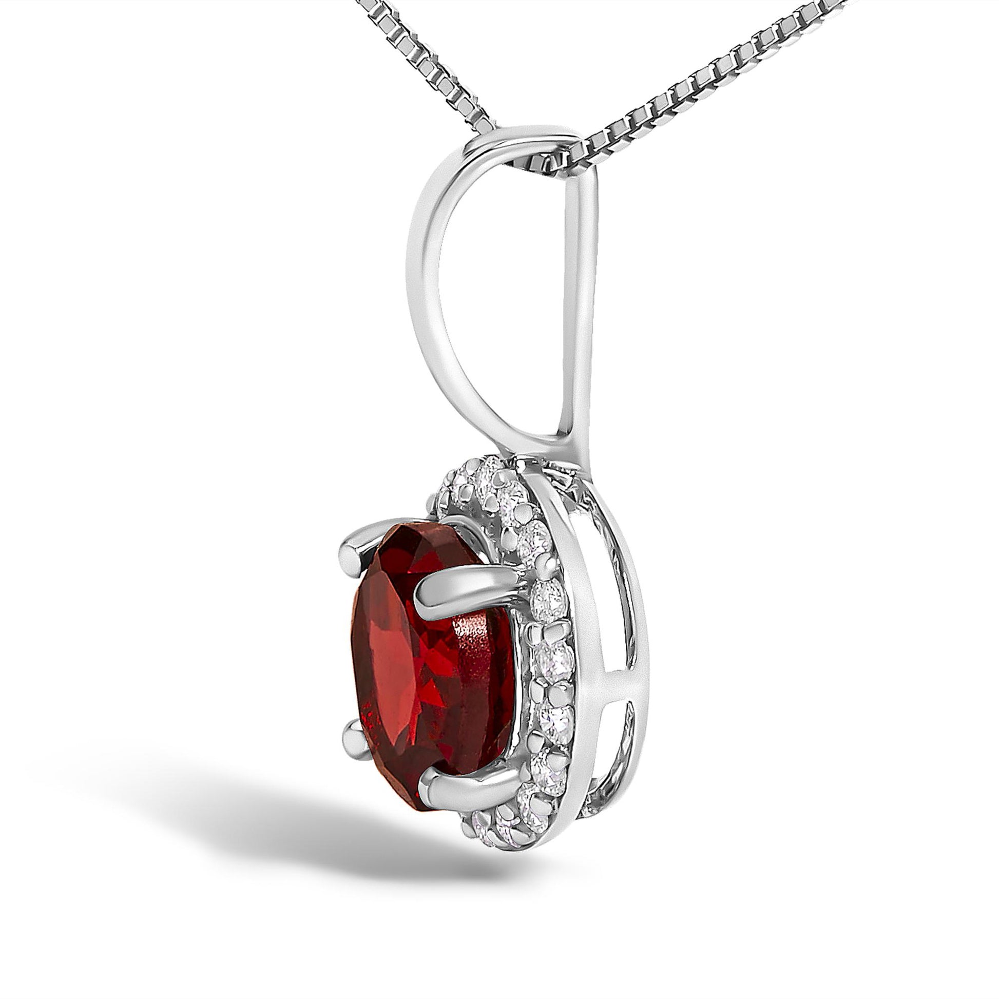 Close-up front angle of a white metal necklace pendant featuring a round red gemstone in a four-prong setting, surrounded by a halo of small round white gemstones in a shared prong setting, shown against a white background.