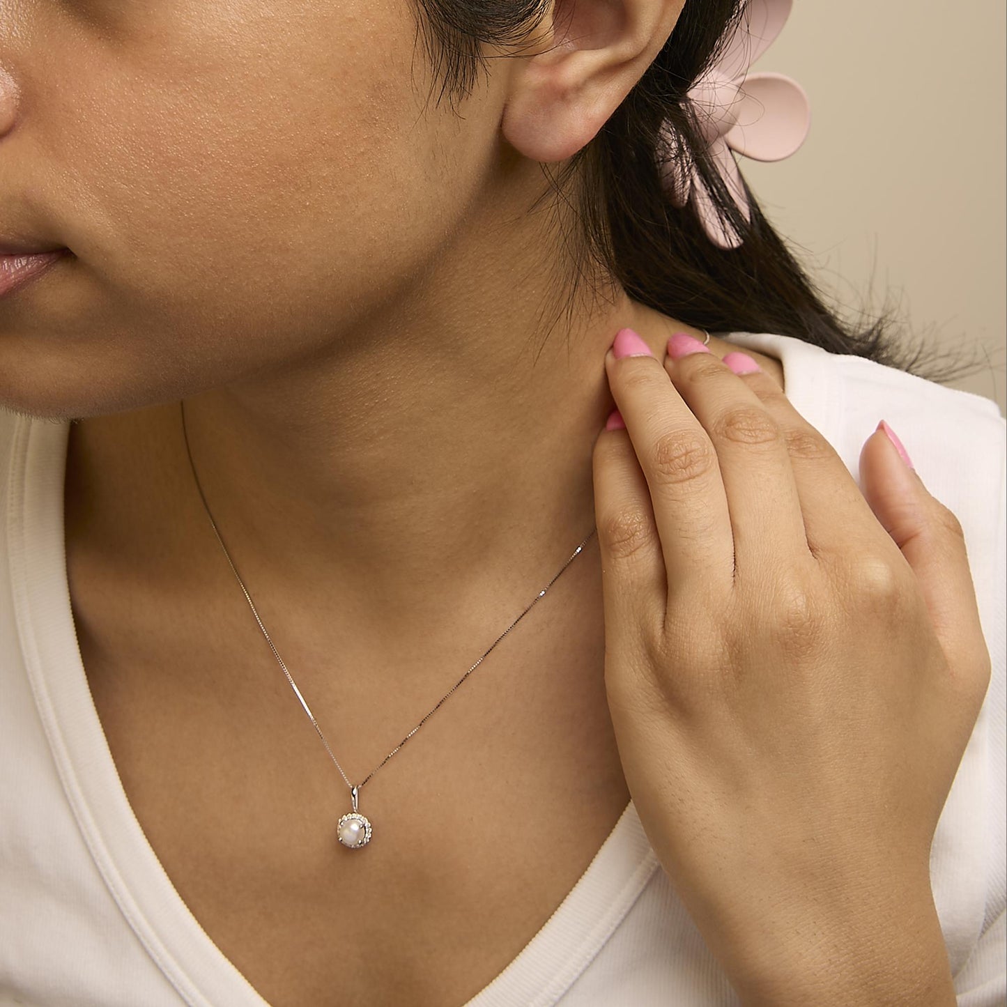 Close-up front angle of a model wearing a white necklace with a round central gemstone surrounded by white round gemstones in a shared prong setting.