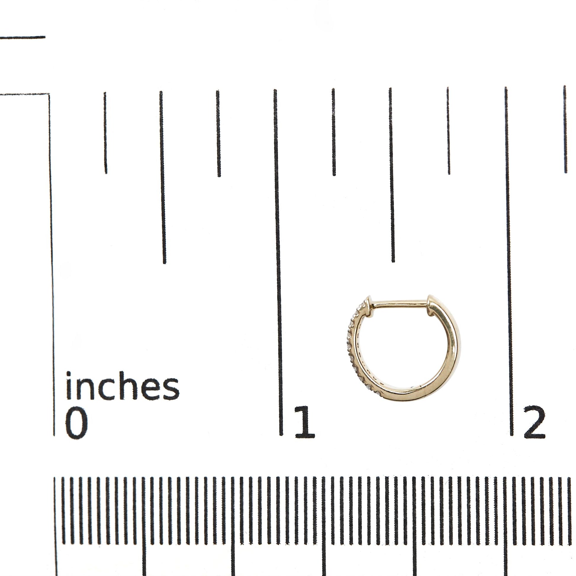 Close-up front angle of small yellow hoop earring with white round gemstones in pave setting, placed on a ruler for size reference.
