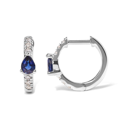 Front and side view of white metal hoop earrings with round white gemstones in pave setting and a pear-shaped blue gemstone in three-prong setting at the center.