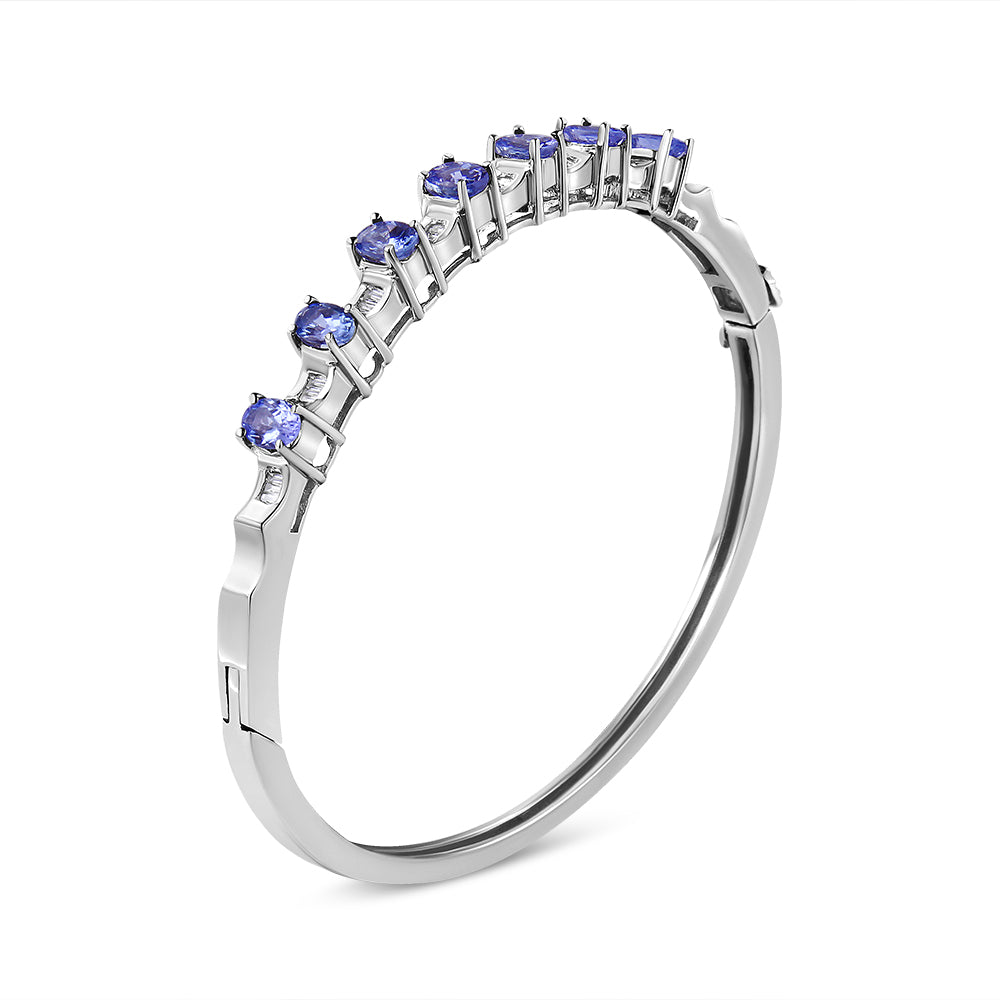 White metal bracelet with blue oval gemstones in prong setting and white baguette gemstones in channel setting, shown at an angle.