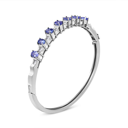 White metal bracelet with blue oval gemstones in prong setting and white baguette gemstones in channel setting, shown at an angle.