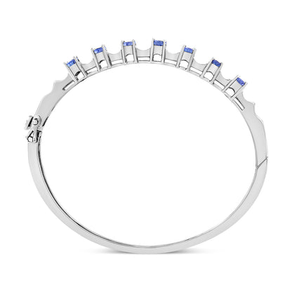White metal bracelet shown from top angle, featuring oval blue gemstones in prong settings and white baguette-shaped gemstones in channel settings.