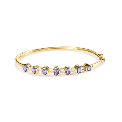 Yellow metal bracelet with oval purple gemstones in bezel settings and white baguette-shaped gemstones in channel settings, shown from a front angled view.