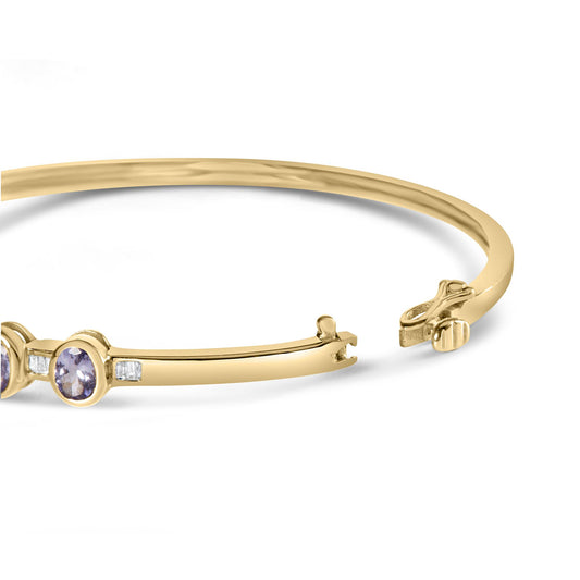 Yellow metal bracelet with oval purple gemstones in bezel settings and small white baguette-shaped gemstones in channel settings, shown from a side angle with open clasp.