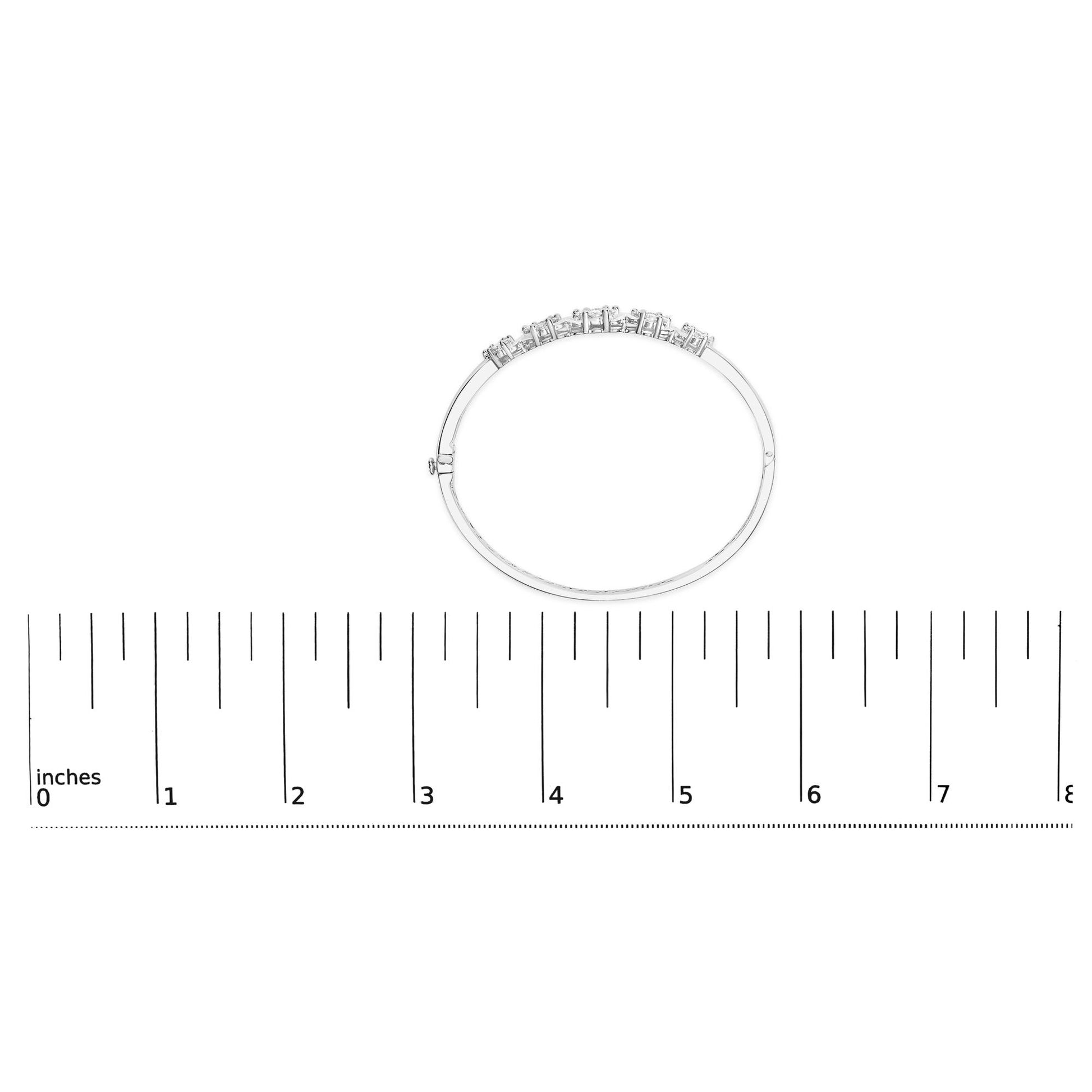 White metal bracelet with round white gemstones in prong settings, shown flat on a ruler for size reference, top-down view.