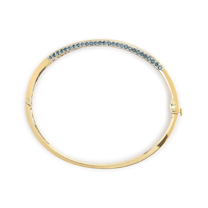 Top-down view of a yellow bracelet with a curved row of round blue gemstones in a pave setting along the upper edge.