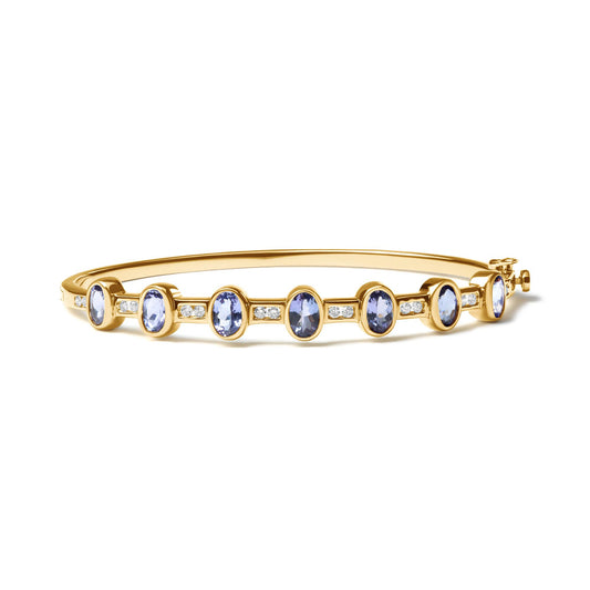 Yellow bracelet with oval blue gemstones in bezel settings and round white gemstones in channel settings, shown at a slight side angle.