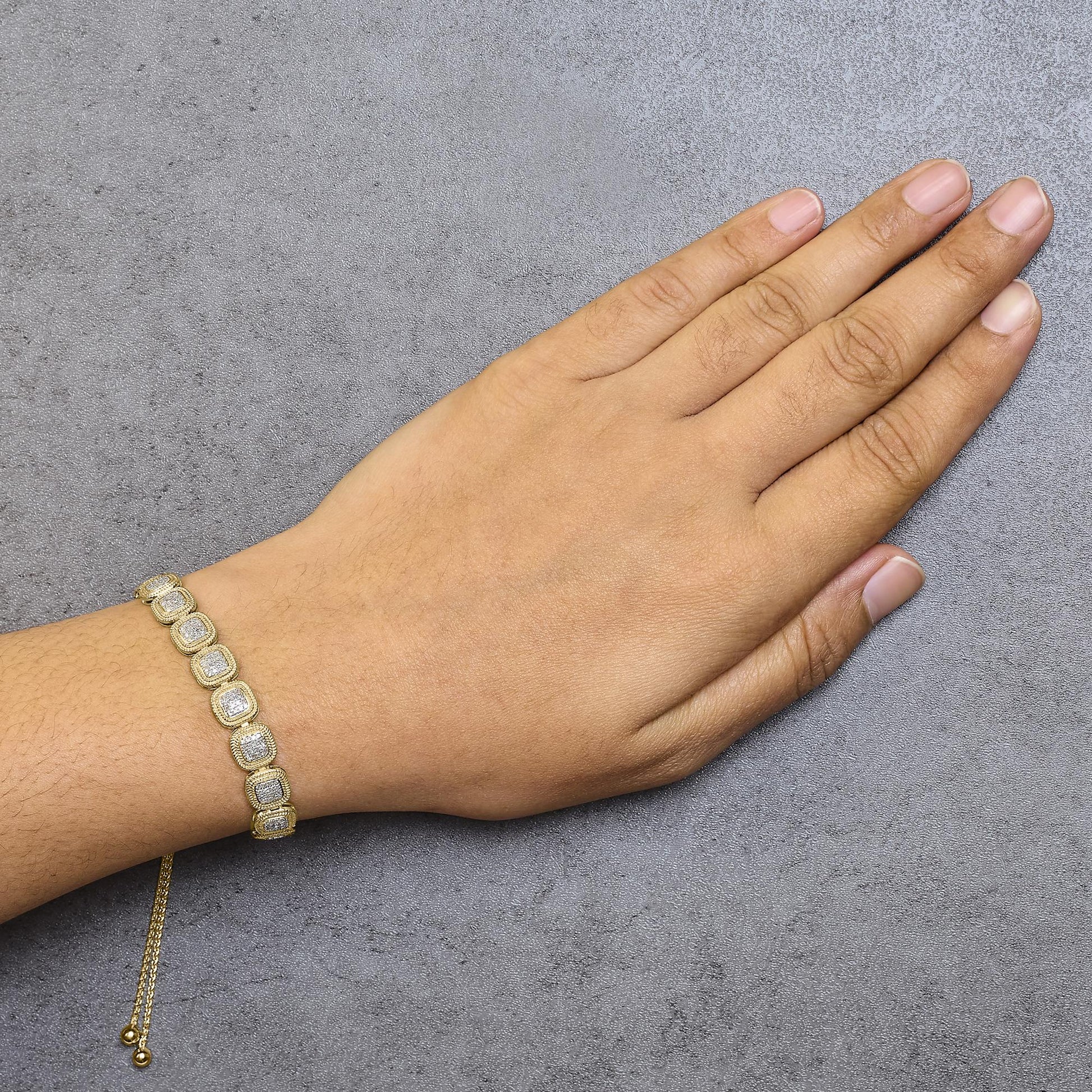 Yellow metal bracelet with square-shaped links featuring white gemstones in prong settings, worn on a model's wrist, side top-down angle.