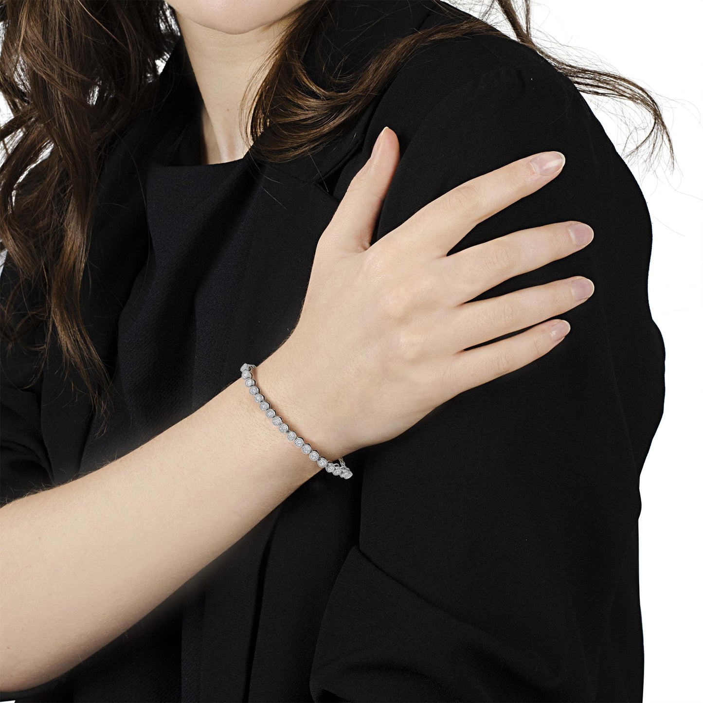 Close-up angled shot of a wrist wearing a white metal bracelet featuring round white gemstones in a miracle setting.