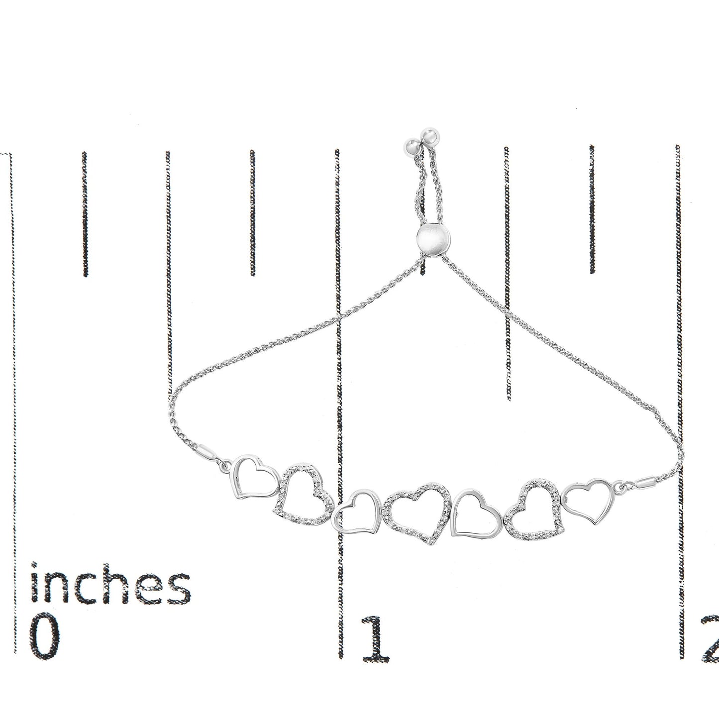 White metal bracelet with alternating open heart shapes, some set with small round white gemstones, shown flat on a ruler from a top-down angle.