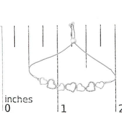 White metal bracelet with alternating open heart shapes, some set with small round white gemstones, shown flat on a ruler from a top-down angle.
