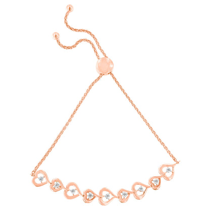 Rose-colored bracelet with interconnected heart shapes, each featuring a round white gemstone in prong setting, shown in a flat lay from above.