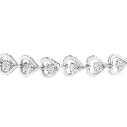 Close-up front view of a white metal bracelet featuring linked open heart shapes, each set with a round white gemstone in a miracle setting.
