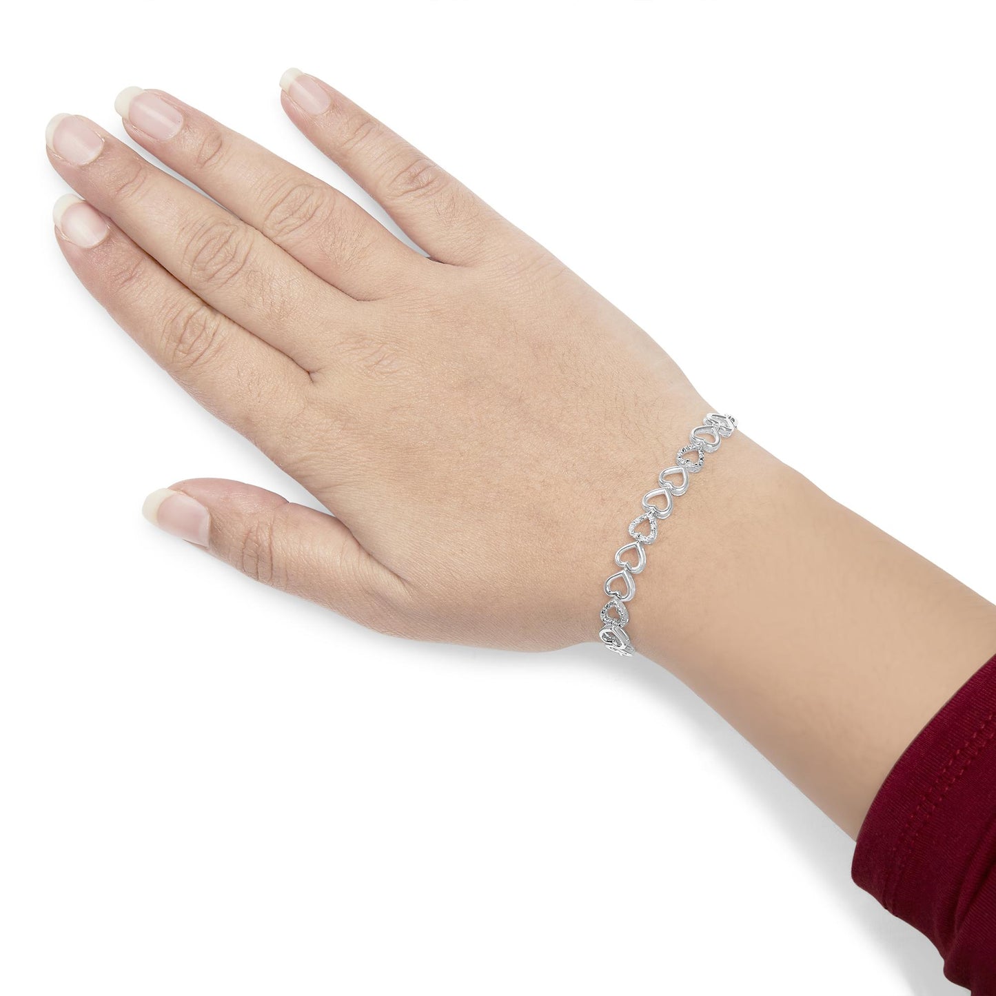 White metal bracelet with linked heart shapes, some accented with white round gemstones in prong settings, shown on a model's wrist from a top angle.