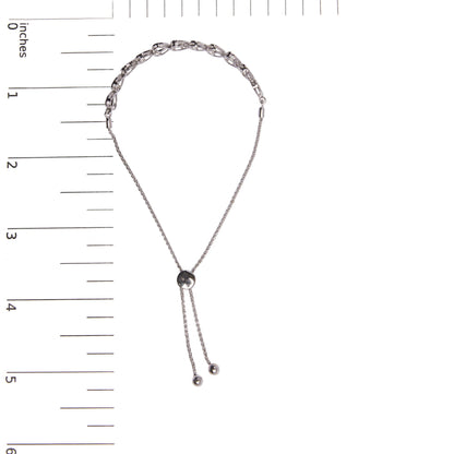 Top down view of white metal bracelet with two styles of round white gemstones in prong settings, shown on a ruler for size reference.