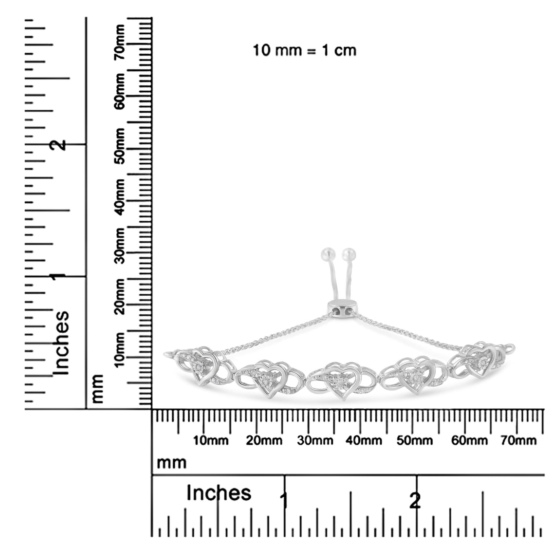 White metal bracelet with heart-shaped links featuring round white gemstones, shown on a ruler for size reference, front angle.