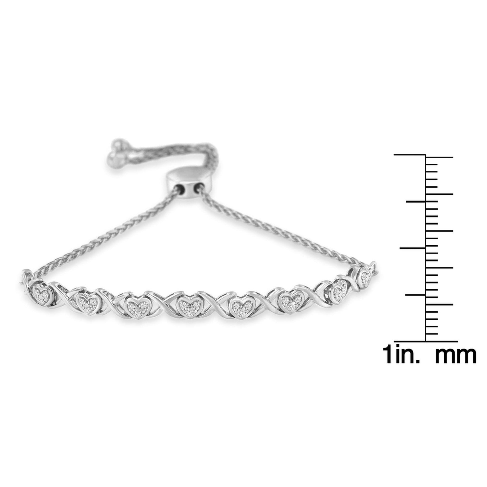 White metal bracelet with heart shaped links accented with round white gemstones in pave setting, shown from a front angle, displayed next to a ruler for size reference.