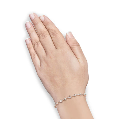 Rose metal bracelet with round white gemstones in pave setting, shown on model's wrist from side angle.
