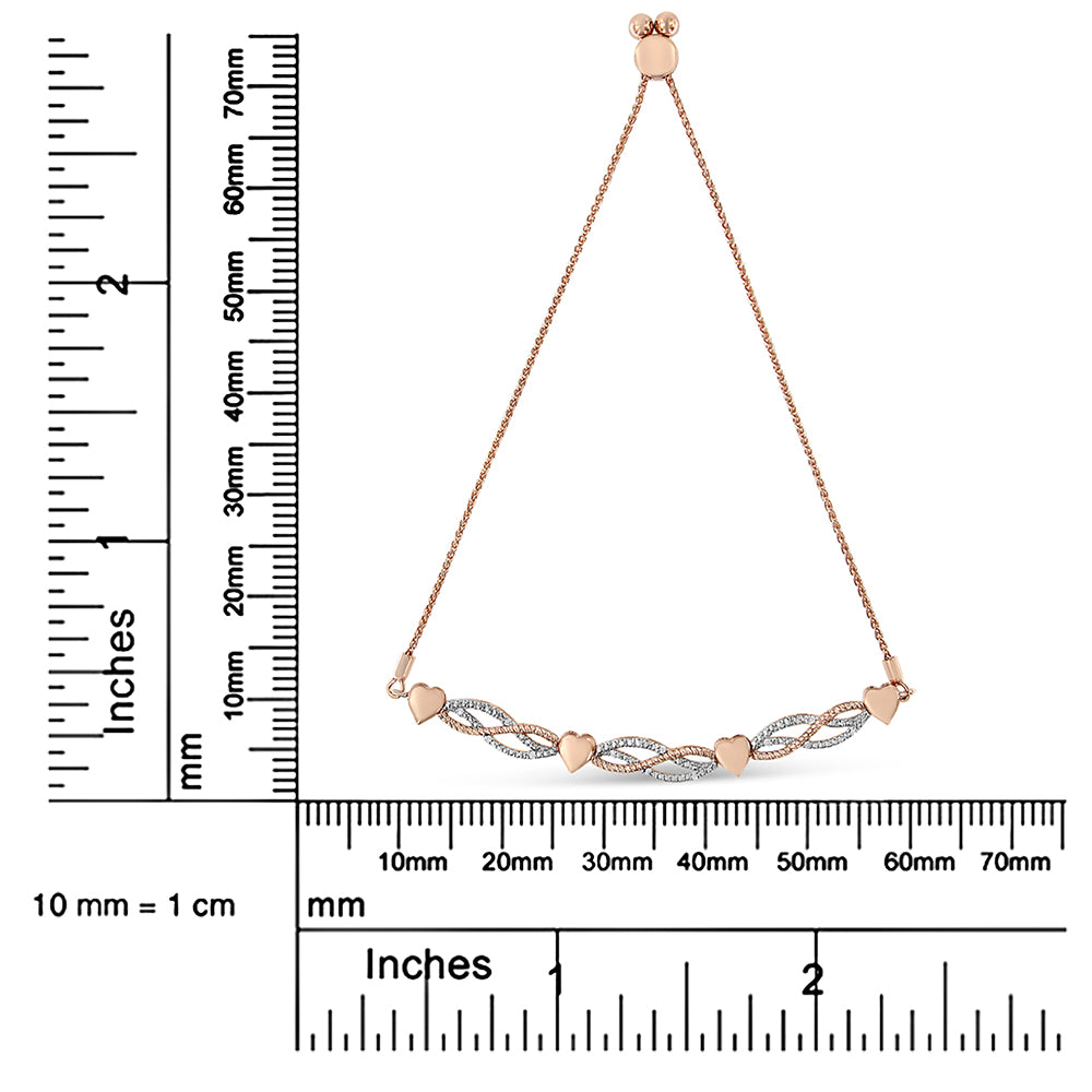Rose-colored bracelet with heart-shaped and braided elements set with round white gemstones, displayed on a ruler for size reference, front angle.