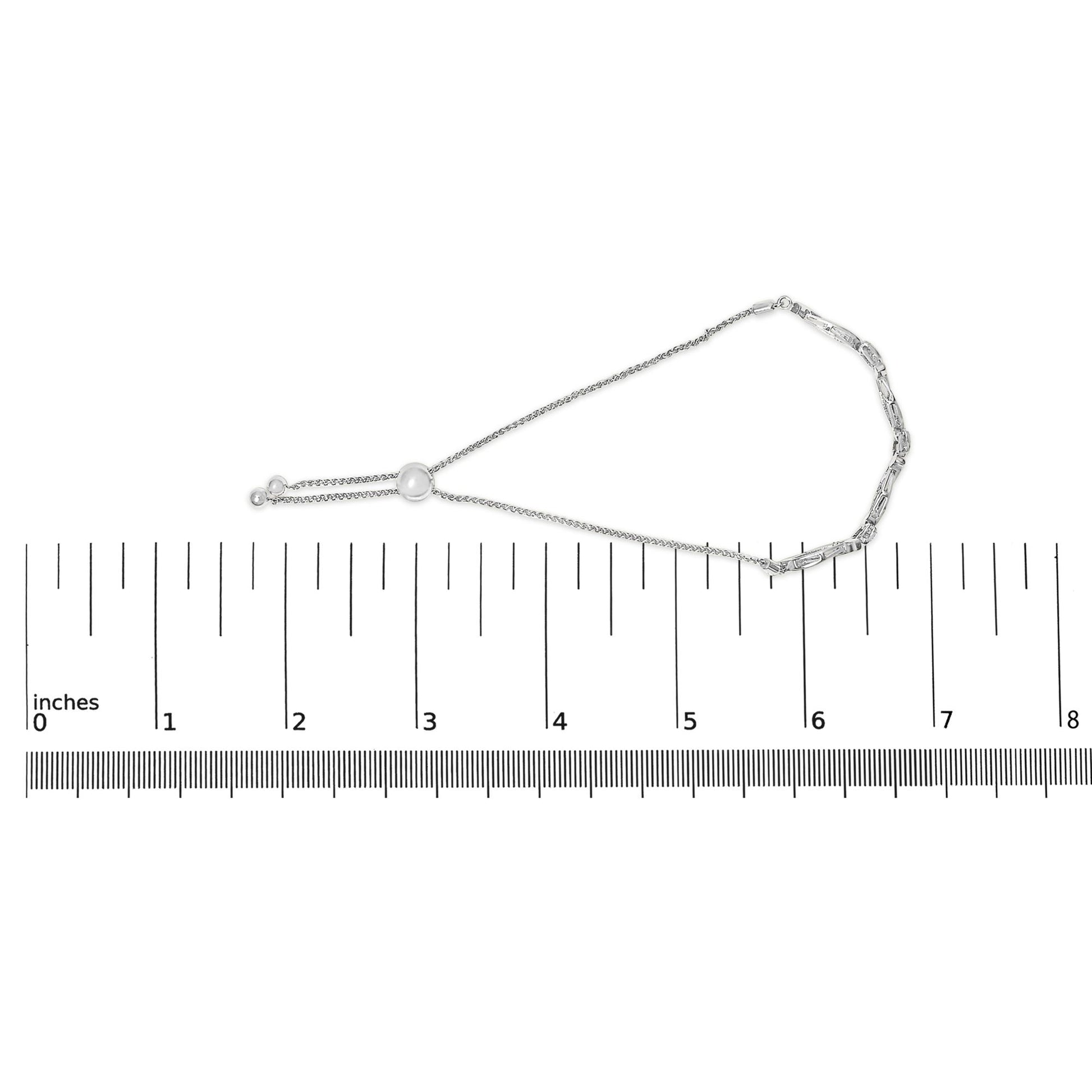 White metal bracelet with linked and chain segments and a sliding bead, featuring round white gemstones in pave setting, displayed flat on a ruler for size reference, top-down angle.