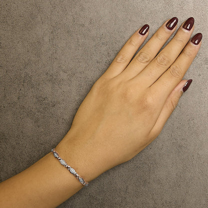 Close-up of a rose-colored bracelet with white round pave-set gemstones worn on a model's wrist, shot from above.