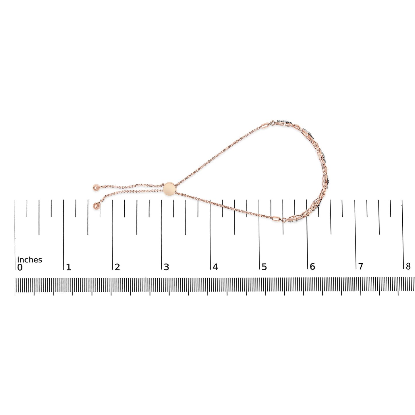 Rose metal bracelet with round white gemstones in pave setting, laid flat on a ruler for size reference, photographed from above.