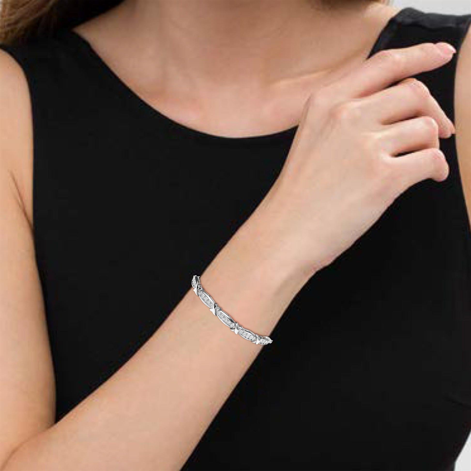 White metal bracelet with oval links and round white gemstones in miracle settings, worn on a model's wrist, shown from a slightly above side angle.