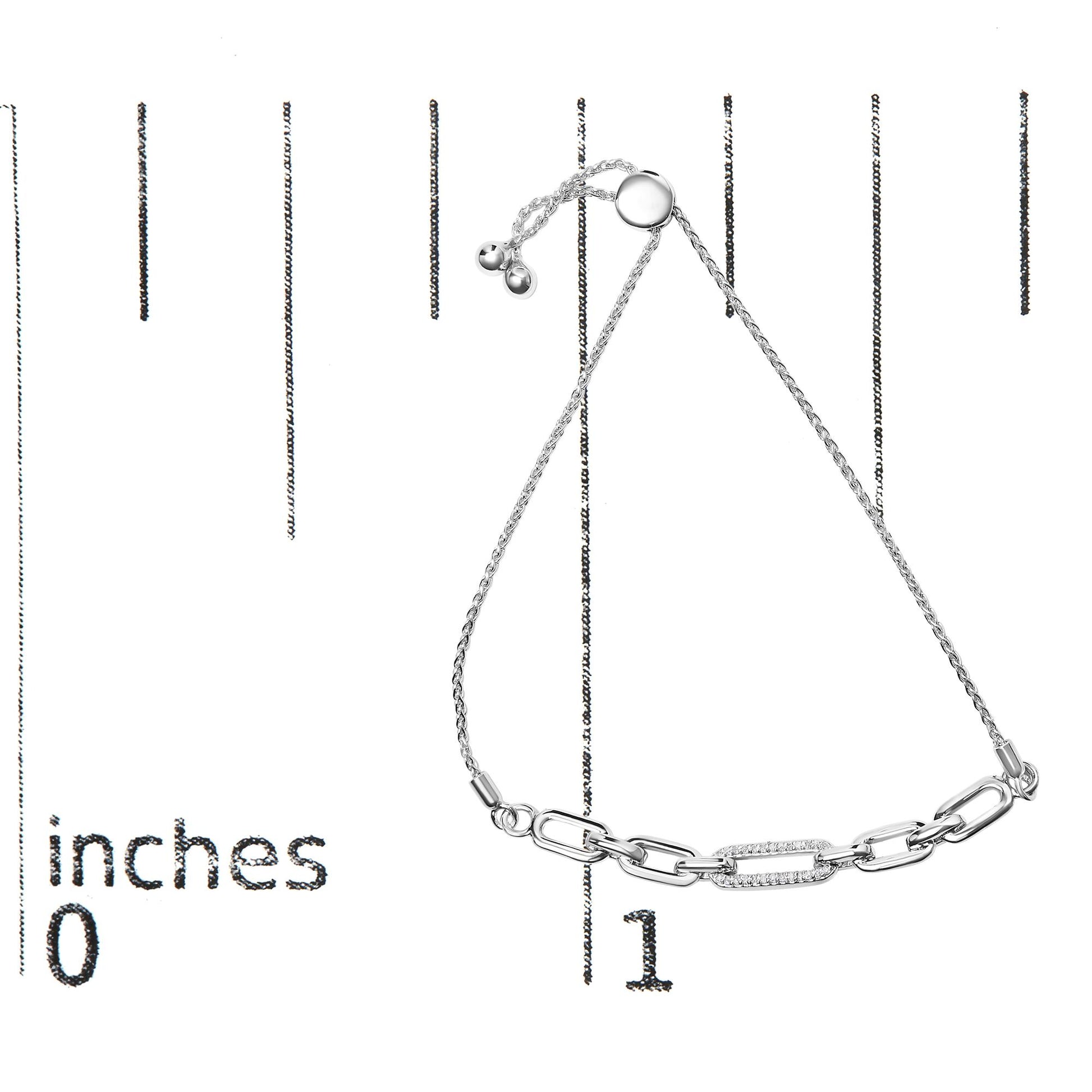 White metal bracelet with chain links, one link adorned with small white gemstones, shown on a ruler for size reference, top view.