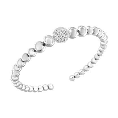 White metal open bracelet composed of round polished beads with one larger bead featuring round white gemstones in pave setting, shown at an angled close-up.