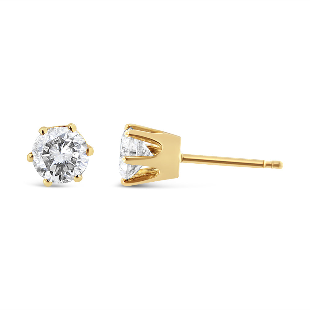 Close-up front and side angle of yellow metal stud earrings with round white gemstones in prong settings.