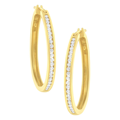 Pair of yellow metal oval hoop earrings with a channel setting of round white gemstones, shown from a front angle.