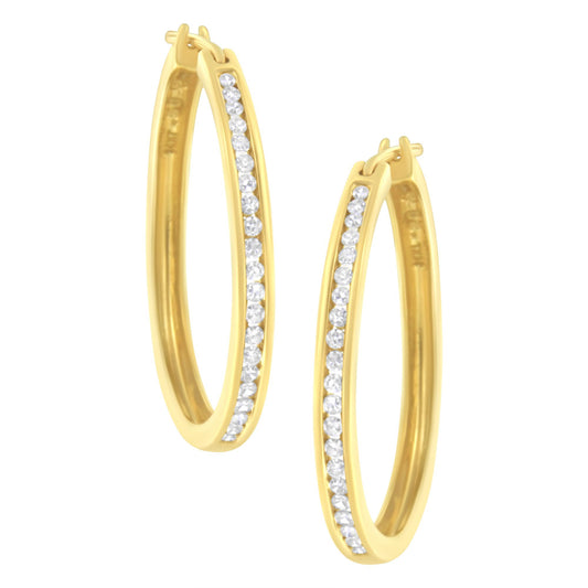 Pair of yellow metal oval hoop earrings with a channel setting of round white gemstones, shown from a front angle.