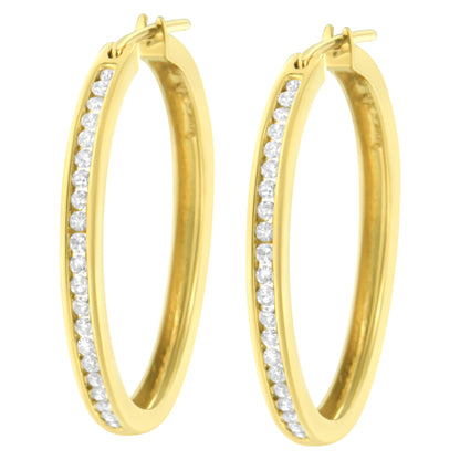 Close-up front angle of a pair of yellow metal hoop earrings with a channel setting of round white gemstones along the outer edge.